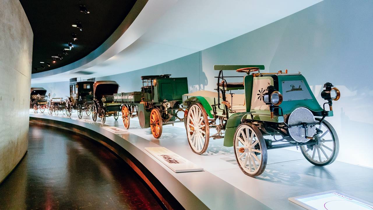 Daimler zmotoryzował biznes w 1899 roku. Wystawa w sali nr 1 Legend Muzeum Mercedesa: Pionierzy - wynalezienie samochodu. Za ciężarówkami Daimlera - Benz Vis-à-Vis i inne samochody z początków motoryzacji 